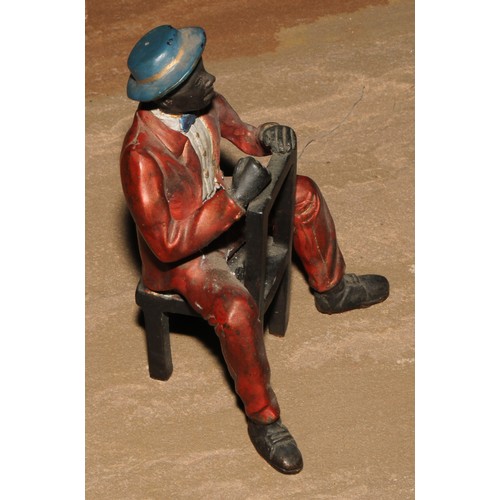 184 - A cold painted bronze, of a Mississippi dandy, seated backwards on a chair, 13.5cm high; another (2)