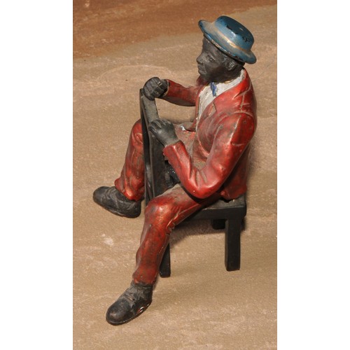 184 - A cold painted bronze, of a Mississippi dandy, seated backwards on a chair, 13.5cm high; another (2)