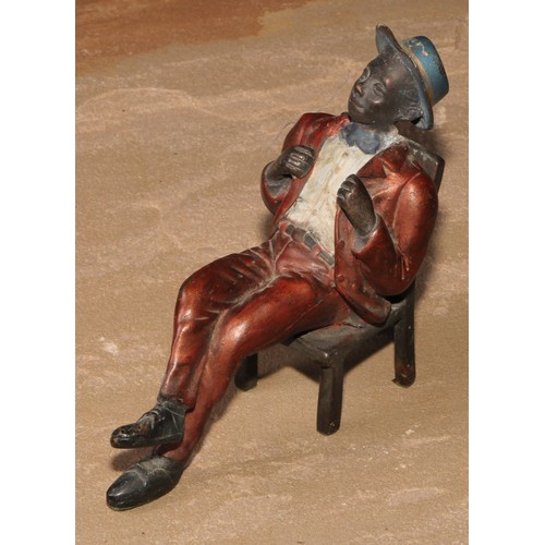 184 - A cold painted bronze, of a Mississippi dandy, seated backwards on a chair, 13.5cm high; another (2)