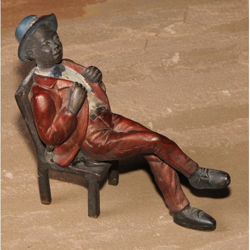 184 - A cold painted bronze, of a Mississippi dandy, seated backwards on a chair, 13.5cm high; another (2)