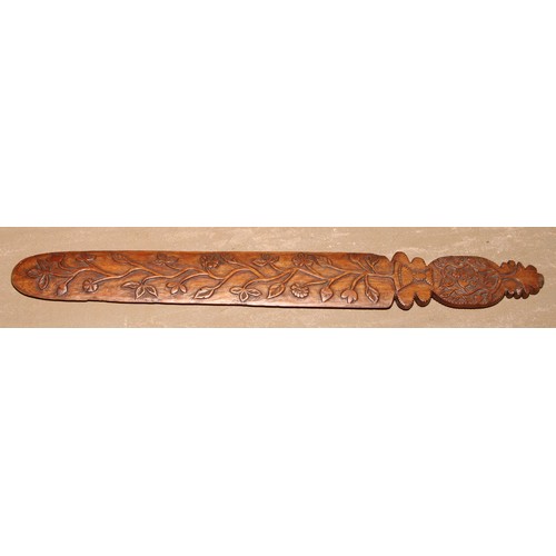 46 - A 19th century folk art page turner, carved in relief with a meandering plant in a vase, 39cm long; ... 