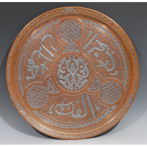 284 - A Middle Eastern silver damascened copper circular tray, inlaid in the Islamic taste with Arabic scr... 