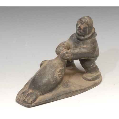 825 - An Inuit soapstone carving, of a hunter and a seal, 21cm long, label for Canadian Inuit Art, mid 20t... 