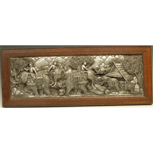 492 - An Indian repousse panel, in bold relief with figures riding elephants, 18cm x 58.5cm, oak frame