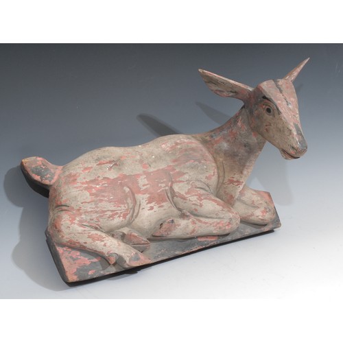 65 - A 19th century Indian polychrome painted wall boss, carved as a recumbent deer, 46cm wide