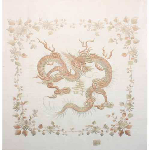 162 - A Chinese needlework picture, worked in two-tone threads with a ferocious dragon, within a flowering... 