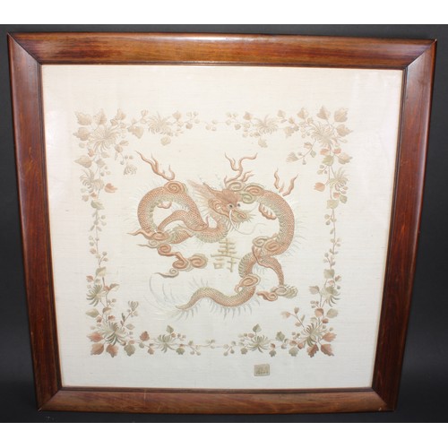 162 - A Chinese needlework picture, worked in two-tone threads with a ferocious dragon, within a flowering... 