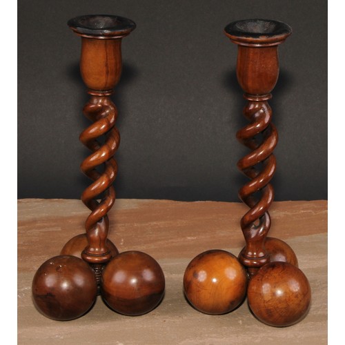 341 - A pair of Middle Eastern olivewood open-twist candlesticks, each triform base composed of three sphe... 