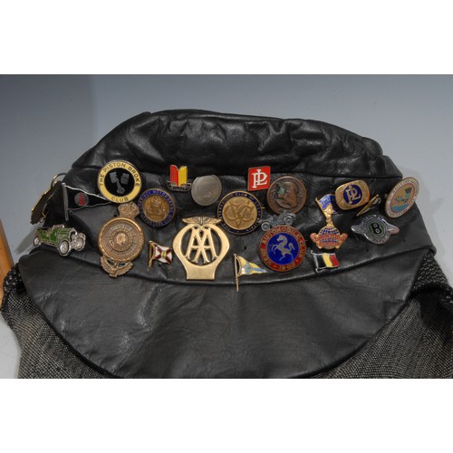 513 - Automobilia - Vintage Motoring - a leather cap laden with a collection of enamel and other badges, K... 