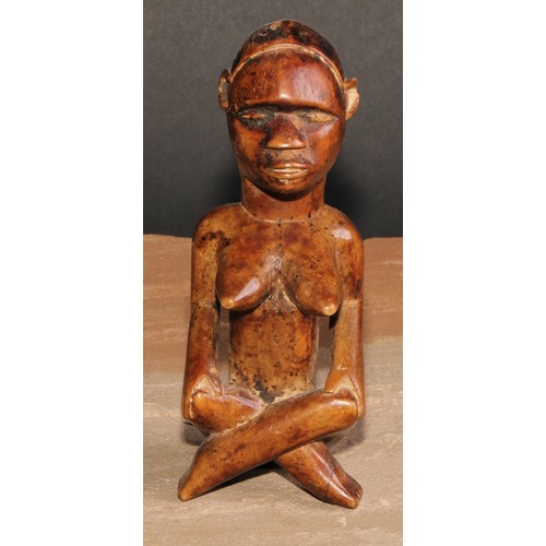 844 - Tribal Art - an African female figure, seated, cross-legged, 15cm high