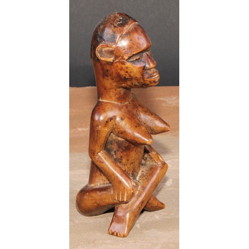 844 - Tribal Art - an African female figure, seated, cross-legged, 15cm high