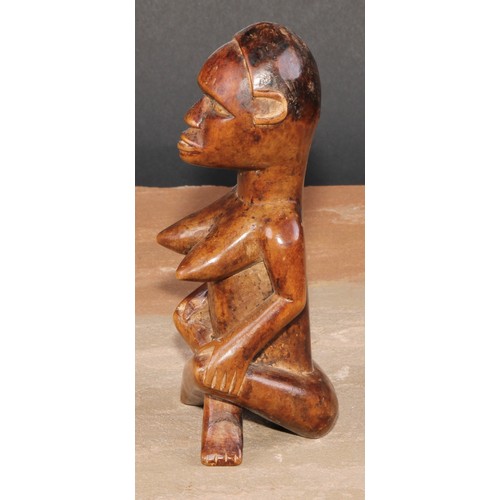 844 - Tribal Art - an African female figure, seated, cross-legged, 15cm high