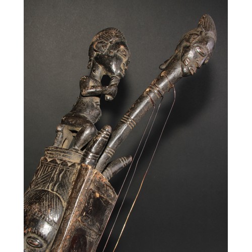 843 - Tribal Art - an African Domu type harp form instrument, carved with masks and figures, 47cm long, po... 