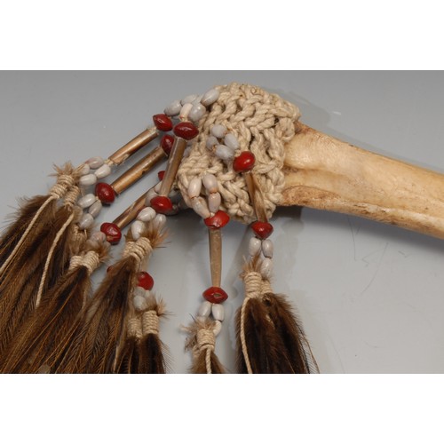 836 - Tribal Art - a Papua New Guinea Cassowary bird bone dagger, embellished with feathers and knotted se... 