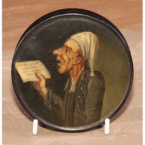 86 - A 19th century papier mache circular snuff box, the cover painted with a ban singing from sheet musi... 