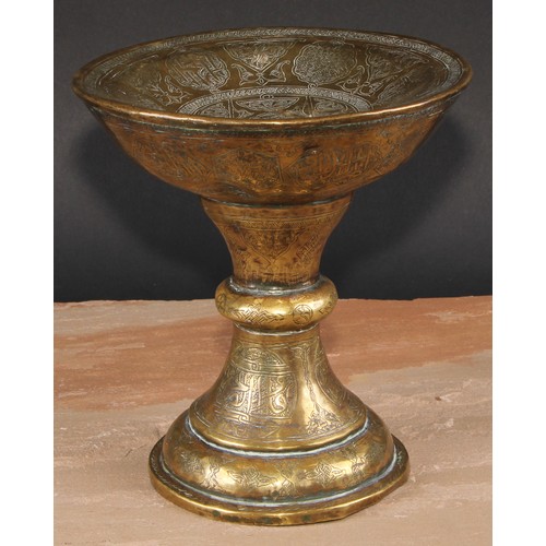 282 - A Middle Eastern brass pedestal stand, profusely chased and engraved in the Islamic taste with Arabi... 