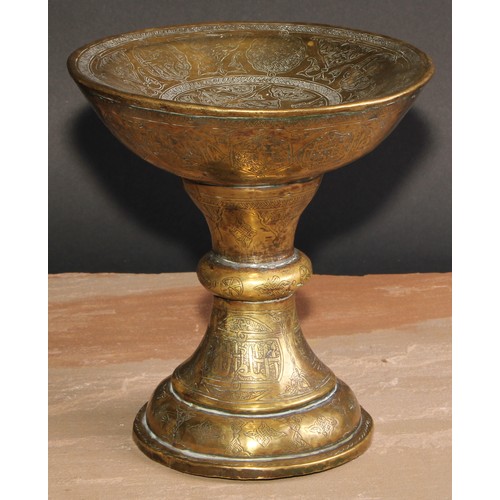 282 - A Middle Eastern brass pedestal stand, profusely chased and engraved in the Islamic taste with Arabi... 