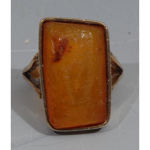 778 - Natural History - an unmarked gold ring, set with an amber specimen containing an insect, the table ... 