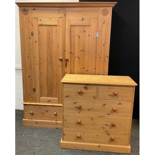14 - A pine two piece bedroom suite, comprising double wardrobe, with carved roundel detailed corners, pa... 