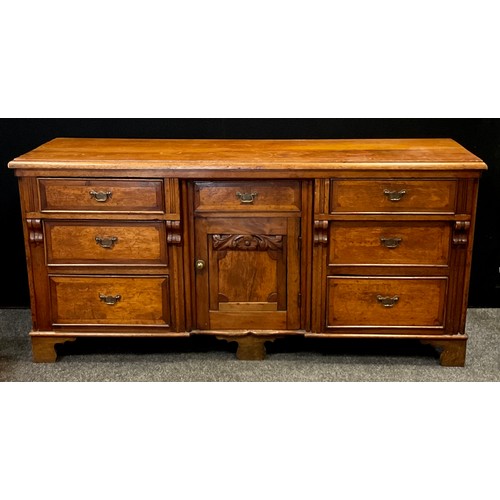 35 - A 20th century crossbanded oak low dresser, with an arrangement of seven drawers flanking central cu... 
