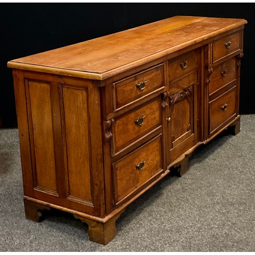 35 - A 20th century crossbanded oak low dresser, with an arrangement of seven drawers flanking central cu... 