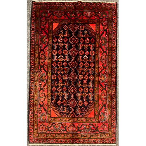 57 - A North west Persian Hamadan rug / carpet, hand-knotted in deep tones of red, brown, and blue, on a ... 