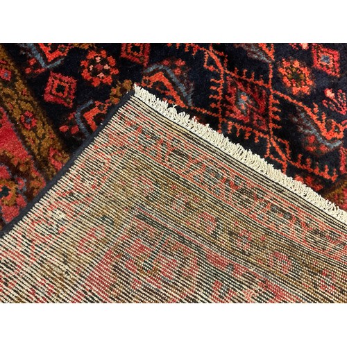 57 - A North west Persian Hamadan rug / carpet, hand-knotted in deep tones of red, brown, and blue, on a ... 