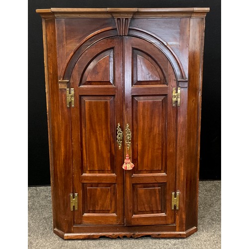 63 - A early 20th century mahogany corner cupboard with three fitted shelves and pair of interior drawers... 