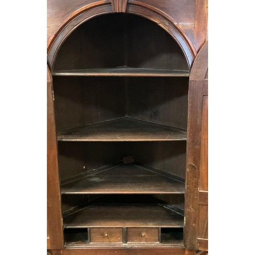 63 - A early 20th century mahogany corner cupboard with three fitted shelves and pair of interior drawers... 