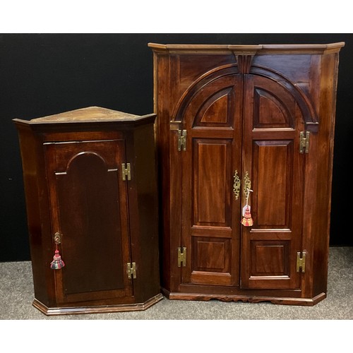 63 - A early 20th century mahogany corner cupboard with three fitted shelves and pair of interior drawers... 