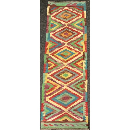 69 - A Turkish Anatolian Kilim runner carpet, knotted with a central row of five diamond-shaped medallion... 