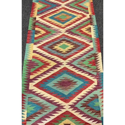 69 - A Turkish Anatolian Kilim runner carpet, knotted with a central row of five diamond-shaped medallion... 