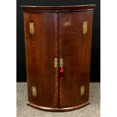 161 - A early 20th century mahogany corner cupboard; cross banded doors with three interior shelves. 103cm... 