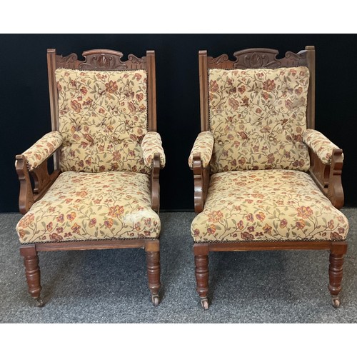 171 - A pair of Edwardian carved oak library chairs, carved cresting rail and arms, button back and stuffe... 