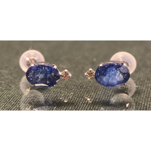 267 - A pair of sapphire and diamond earrings, each with a single oval purply blue sapphire above a round ... 