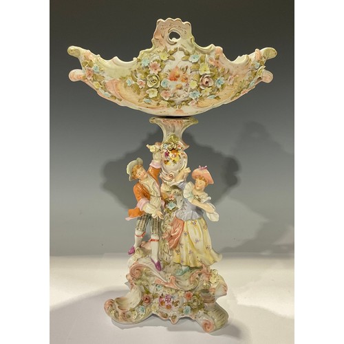 95 - A Dresden table centre, the floral encrusted basket above a figural support, quatrefoil scroll base,... 