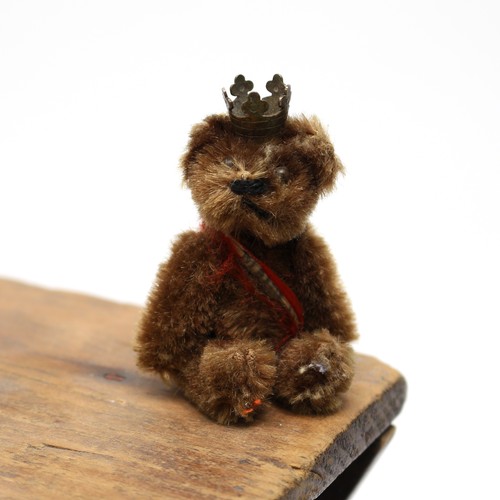 136 - Toys & Juvenalia - a mid 20th century miniature jointed brown mohair teddy bear, pin eyes, wearing a... 