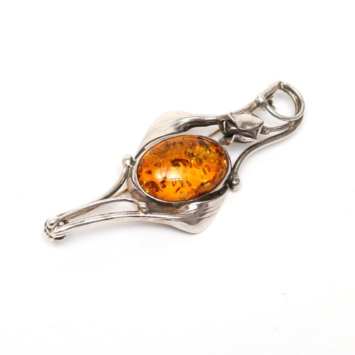 425 - An Art Nouveau style silver brooch, the centre set with an amber type cabochon