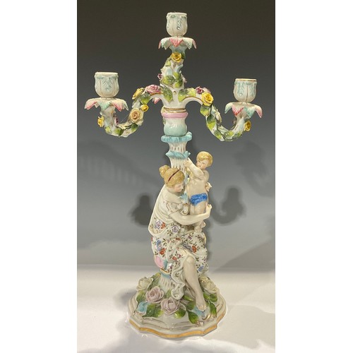 484 - A late 19th century German porcelain floral encrusted three branch candelabra, the figural support w... 