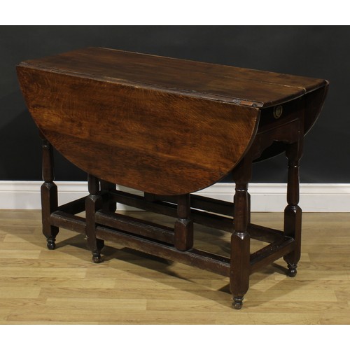 524 - An oak gateleg table, near-oval top with fall leaves, turned and blocked supports, 71cm high, 45cm o... 