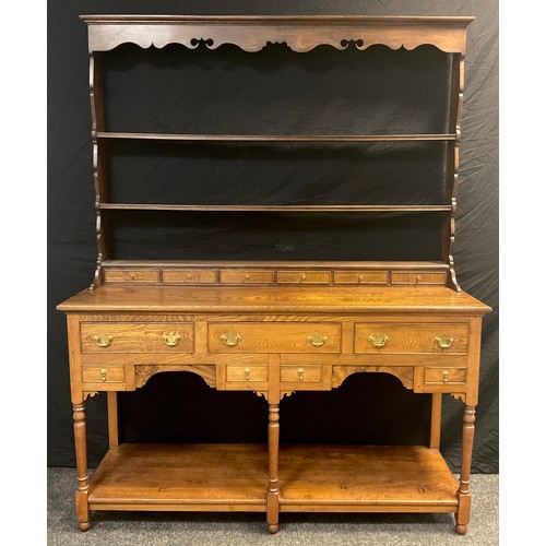 38 - An Elm Welsh dresser, plate-rack top with moulded cornice, shaped apron, three tiers of shelving and... 
