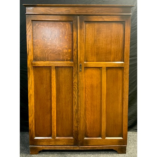 84 - An early 20th century oak Bachelor or Bachelorettes wardrobe, moulded cornice, above pair of panelle... 