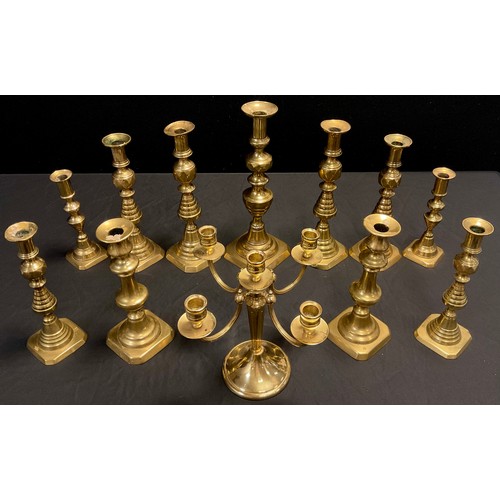 140 - Three graduated pairs of brass candlesticks, ribbed pyramidal stems, canted square bases, the larges... 