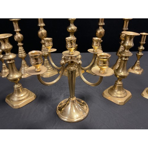 140 - Three graduated pairs of brass candlesticks, ribbed pyramidal stems, canted square bases, the larges... 