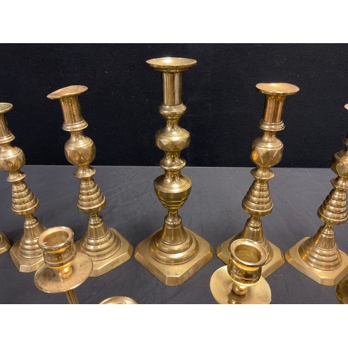 140 - Three graduated pairs of brass candlesticks, ribbed pyramidal stems, canted square bases, the larges... 