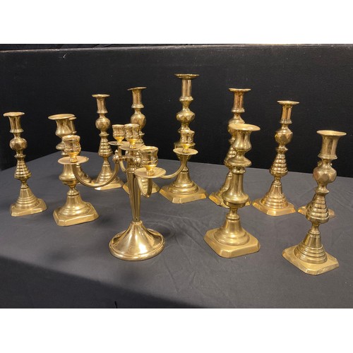 140 - Three graduated pairs of brass candlesticks, ribbed pyramidal stems, canted square bases, the larges... 