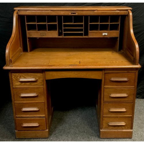 141 - A oak serpentine roll top desk; central drawer to frieze and four graduated drawers to each pedestal... 