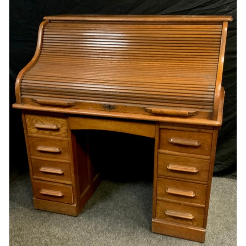 141 - A oak serpentine roll top desk; central drawer to frieze and four graduated drawers to each pedestal... 