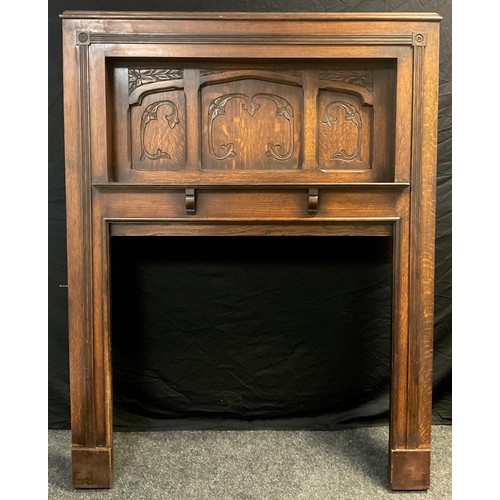 145 - An early 20th century large oak fire surround/ Chimney-piece, recessed top with carved panels, and s... 