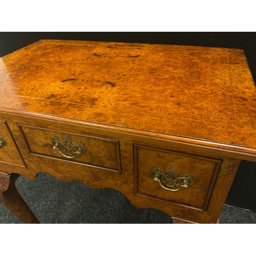 146 - A reproduction burr elm lowboy, oversailing top above three frieze drawers, shaped apron, shell carv... 